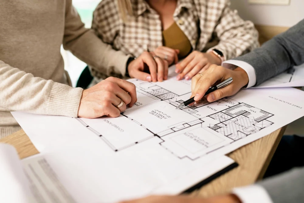 Drei Personen zeigen mit Stift und Finger